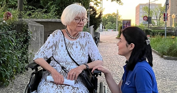 Mitarbeitende geht mit im Rollstuhl sitzender Seniorin spazieren