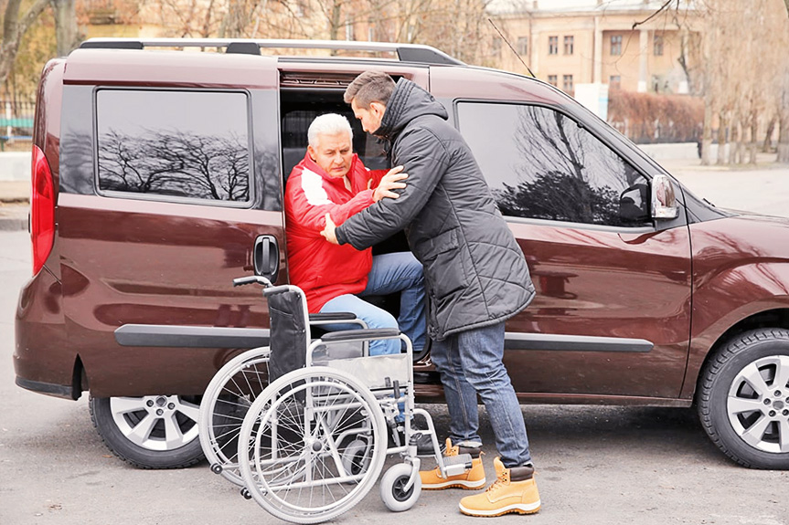 Spitex Fahrdienst – Person wird aus dem Auto in den Rollstuhl geholfen