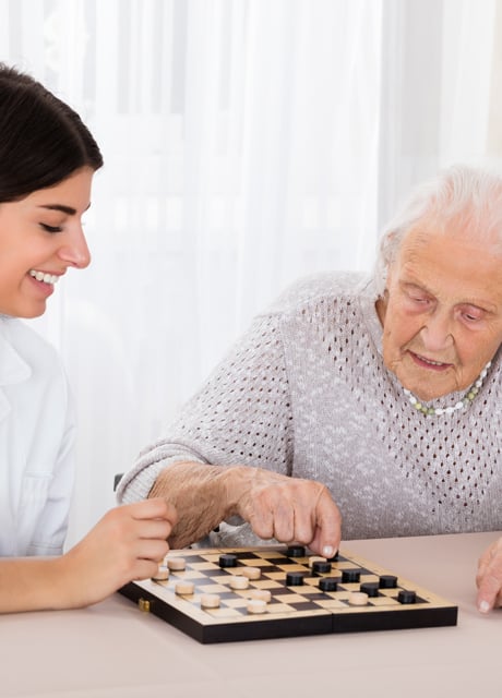 Fachkraft Betreuung spielt mit einer älteren Dame Schach