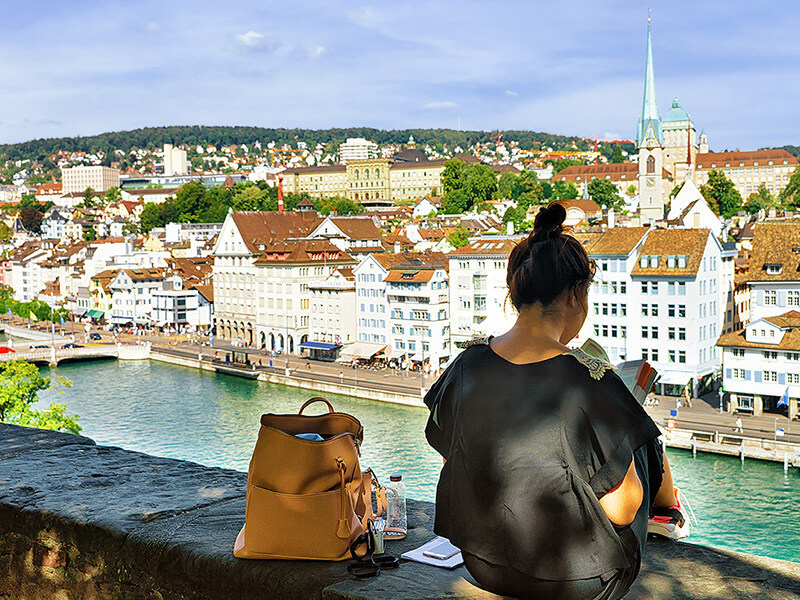 Eine Person überblickt Zürichs Altstadt mit persönlichen Gegenständen auf einer Mauer, symbolisch für Spitex im Kanton und deren Gemeinschaftsnähe.