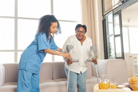 Pflegefachfrau reicht Klientin die Gehstöcke