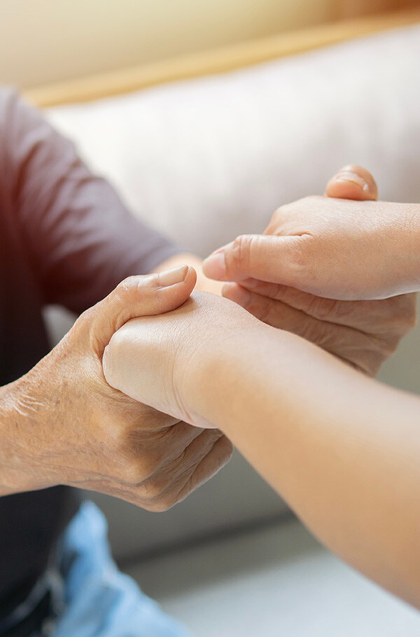 Nahaufnahme der Hände einer privaten Spitex-Pflegekraft, die liebevoll die Hand eines älteren Menschen hält.
